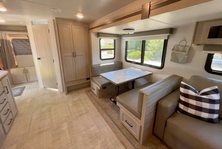 Modern RV rental interior with light wood cabinetry, gray dinette, and cozy living space.. Forest River Rockwood Roo 235S