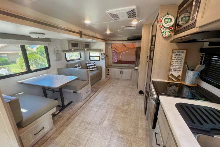 Inside this modern rv rental: dinette, sofa, kitchen, and a cozy pop-out bed area are visible in this bright interior.. Forest River Rockwood Roo 235S