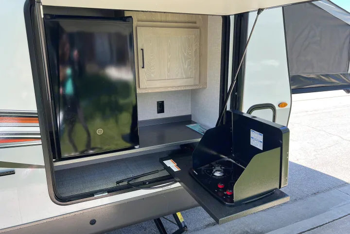 An RV rental's exterior pull-out kitchen, complete with a mini-fridge and stove, offers convenience for camping.. Forest River Rockwood Roo 235S