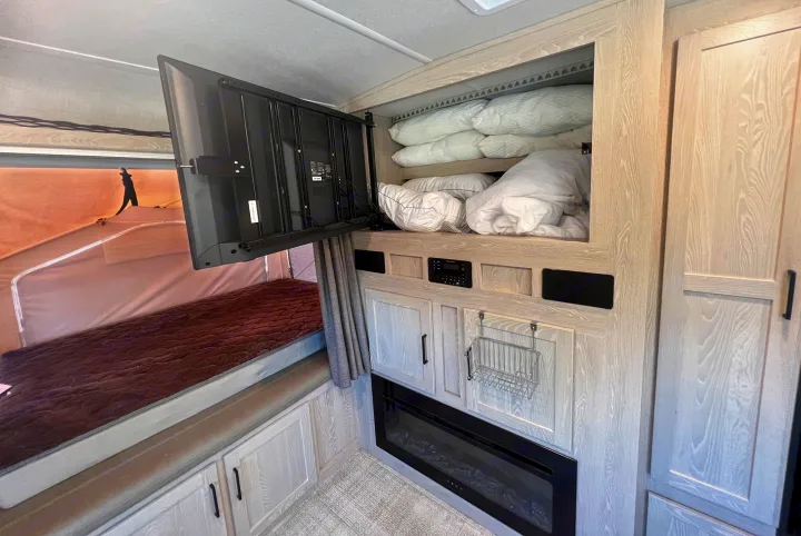 Explore this RV rental's interior: swing-out TV, overhead bedding storage, cabinets, and a modern electric fireplace.. Forest River Rockwood Roo 235S