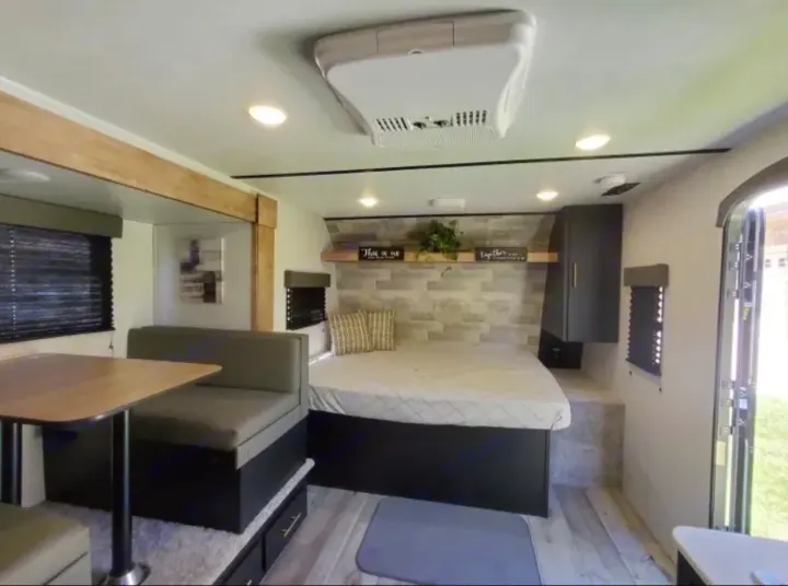 Spacious rv rental interior featuring a cozy bed, dinette area, and modern amenities. Perfect for your next adventure.. Keystone RV Springdale 2022