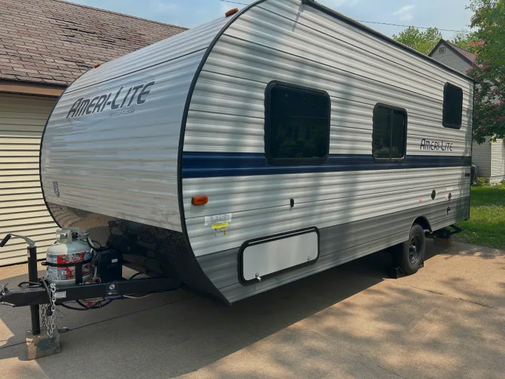 A sleek gray Ameri-Lite travel trailer RV rental, with blue trim and windows, parked on concrete.. Gulf Stream Ameri-Lite Super Lite 2021