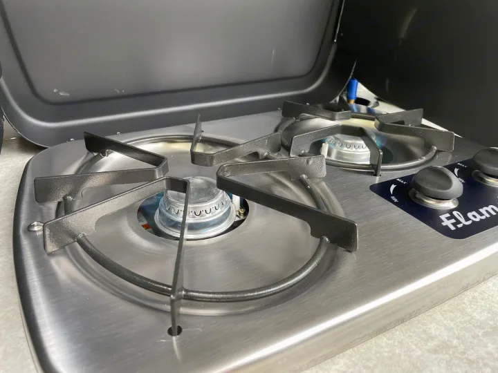 This two-burner portable gas stove, with one burner lit, is perfect for cooking on an RV rental trip.. Braxton Creek Bushwhacker 2022