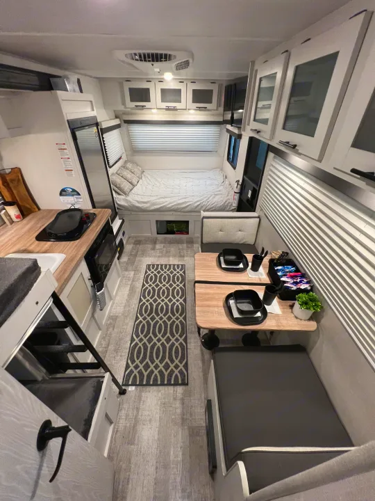 Modern RV rental interior: cozy bedroom, dinette, kitchen, and bunk, offering compact travel comfort.. No Boundaries 16 2023