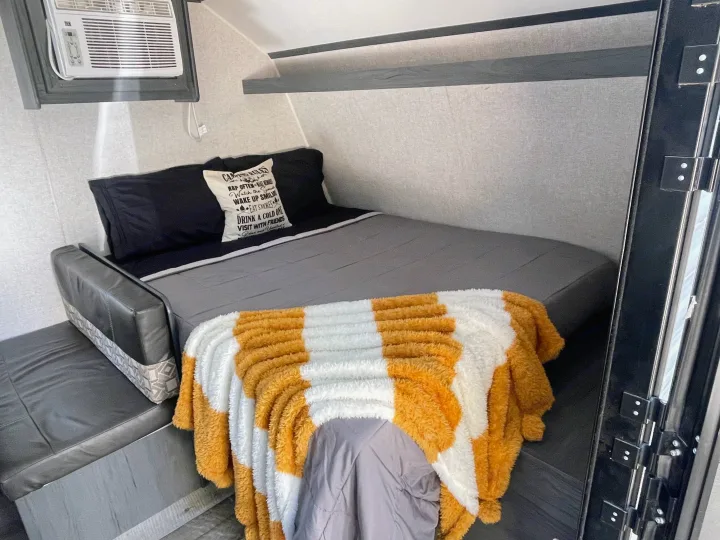 Cozy RV rental interior with a bed, couch, AC, and fluffy blanket for a comfortable, relaxing trip.. Dutchmen Aspen Trail 2021