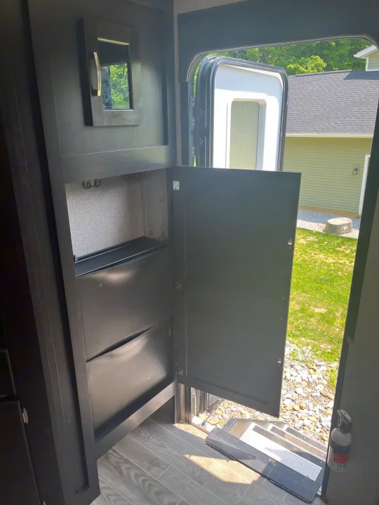 **RV rental**: Interior view of the entrance area with an open door, revealing exterior steps, and built-in storage with a mirror.. Jayco Jay Flight 2021