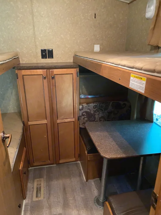 RV rental interior features comfortable bunk beds, a central wardrobe, and a functional dinette, ideal for travel.. Crossroads RV Sunset Trail Super Lite 2012