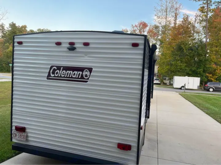 Rear view of a white Coleman RV/camper trailer parked on a driveway. Consider it for your next RV rental!. Dutchmen Coleman Lantern LT 2020