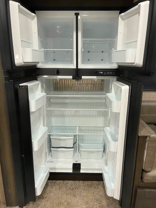 Empty four-door RV refrigerator, showing shelves and bins, ready for your next rv rental adventure.. Grand Design Reflection 2021
