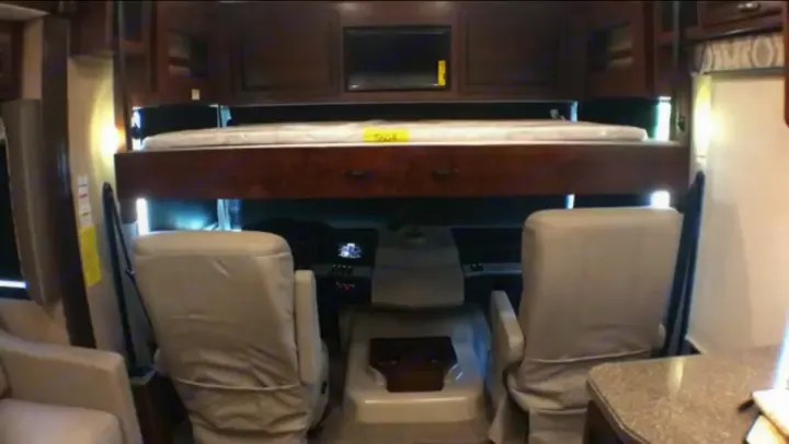 Spacious RV rental cockpit area with overhead bunk bed and TV. Ideal for comfortable travel.. Fleetwood Bounder 2017