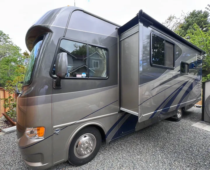 Modern grey and blue motorhome RV rental with extended slide-out, parked on gravel. Ideal for spacious travel adventures.. A.C.E. A.C.E. Motorhome 2013