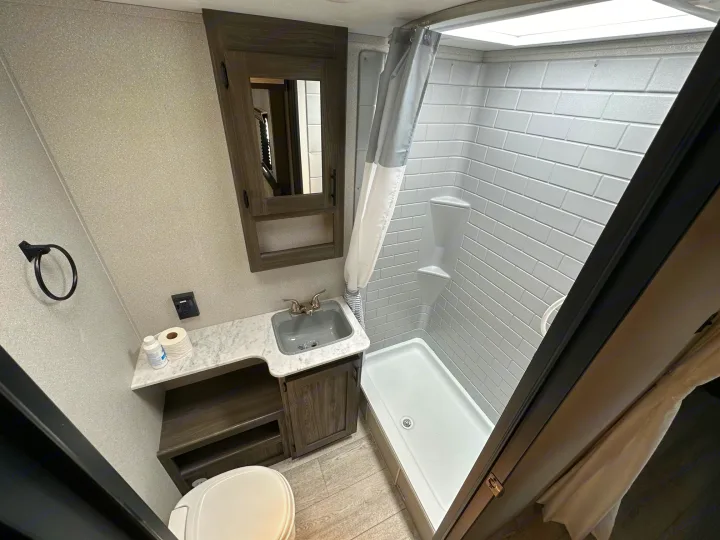 This RV rental bathroom features a compact design with a shower, sink, toilet, and mirror for convenient travel.. Grand River Grand River 33BOK 2021