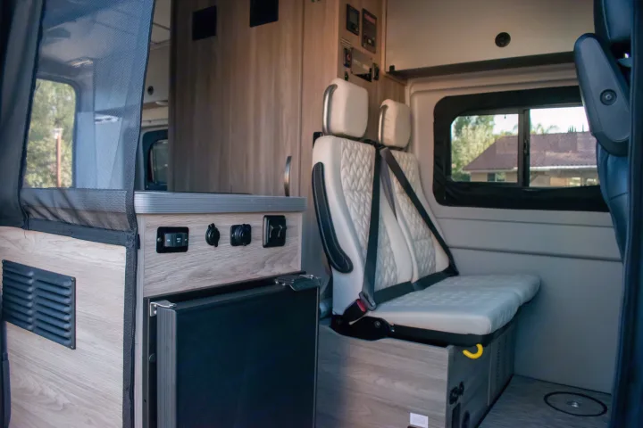 RV rental interior view: Passenger seating, a compact fridge, and convenient power outlets. Ready for your adventure.. Winnebago Solis 59PX 2023