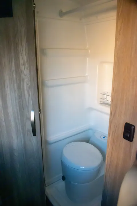 Compact RV rental bathroom with toilet and shower, featuring a functional wet bath design for comfortable travel.. Winnebago Solis 59PX 2023