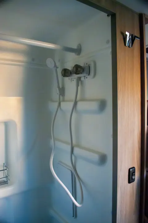 Compact RV rental shower with a handheld showerhead, water controls, and practical storage.. Winnebago Solis 59PX 2023