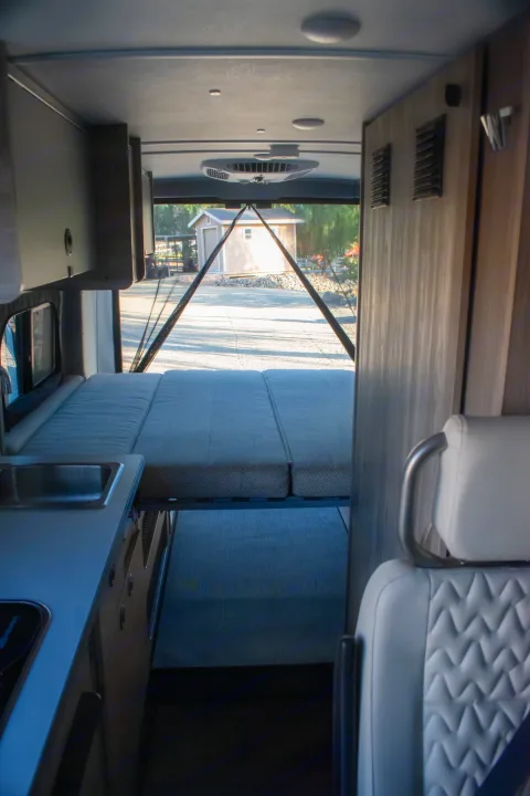 RV rental interior: A versatile space featuring a convertible bed, kitchen area, and open rear doors with an outdoor view.. Winnebago Solis 59PX 2023