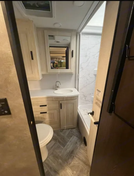 Spacious RV rental bathroom: vanity, sink, toilet, and tiled shower/tub. Ready for your next adventure!. Forester LE 2022