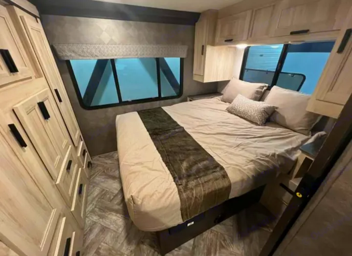 RV bedroom interior showing a comfortable bed, overhead cabinets, and dresser, perfect for your RV rental journey.. Forester LE 2022