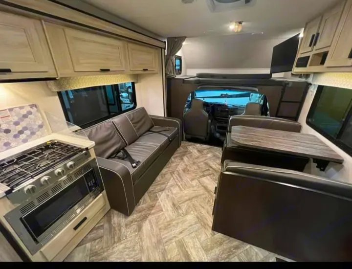 This rv rental interior features a kitchen, sofa, dinette, and overhead bunk. A spacious, modern motorhome living space.. Forester LE 2022