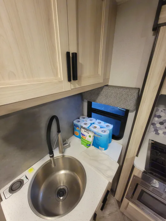 RV rental kitchen showing sink, cabinets, window, RV toilet paper, and wireless charging. Compact and functional.. Forester LE 2022