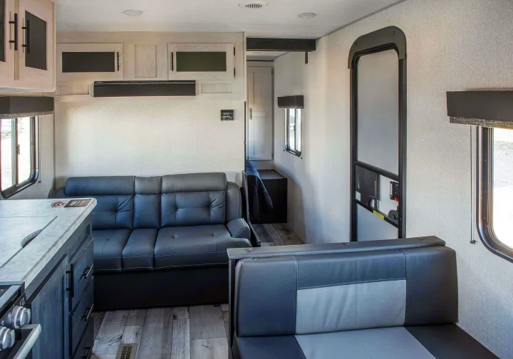 Spacious RV rental interior featuring a gray sofa, modern kitchen counter, dinette, and bright windows.. KZ Sportsmen SE 260BHSE 2022