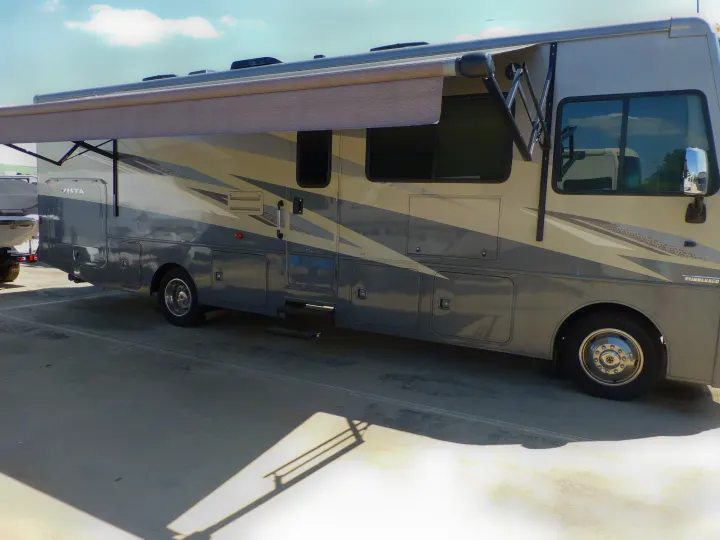 Side view of a large grey Winnebago Vista RV, with an extended awning. Ideal for your next RV rental adventure.. Winnebago Vista 2020