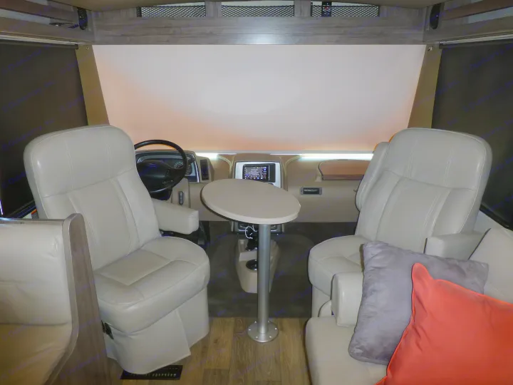 RV rental: Spacious cabin with light leather driver/passenger seats, a table, and dash tech within a motorhome.. Winnebago Vista 2020