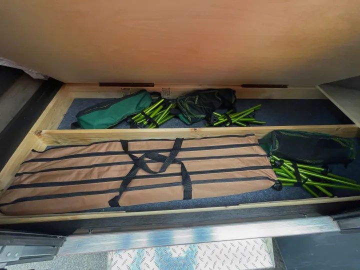 RV rental storage shows neatly stowed camping gear: collapsible chairs, poles, and a large folding bag, likely a table.. Braxton Creek Bushwhacker 2022