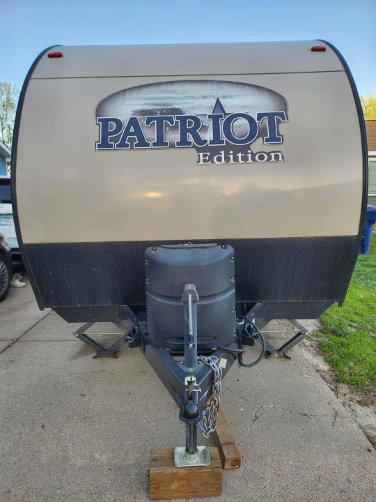 Front of a "Patriot Edition" travel trailer, equipped with propane tanks and leveling jacks. Perfect for an rv rental.. Forest River Cherokee Wolf Pup 2018