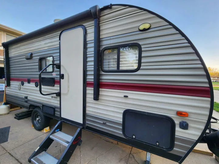 This RV rental travel trailer is parked with its door open and steps down, ready for your next adventure.. Forest River Cherokee Wolf Pup 2018