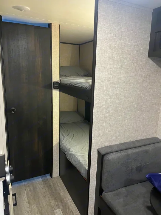 RV rental interior: Bunk beds, dinette, and textured walls in a compact travel trailer's sleeping area.. Jayco Jay Flight SLX 2023