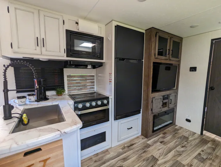 Bright RV rental interior featuring a well-appointed kitchen, entertainment center with TV, and cozy electric fireplace.. Sport Trek Sport Trek Trailer 2021