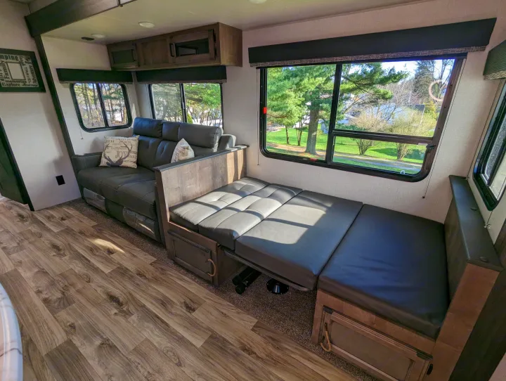 Cozy RV rental: interior features a grey leather sofa converting to a bed, large windows, and wood-look flooring.. Sport Trek Sport Trek Trailer 2021