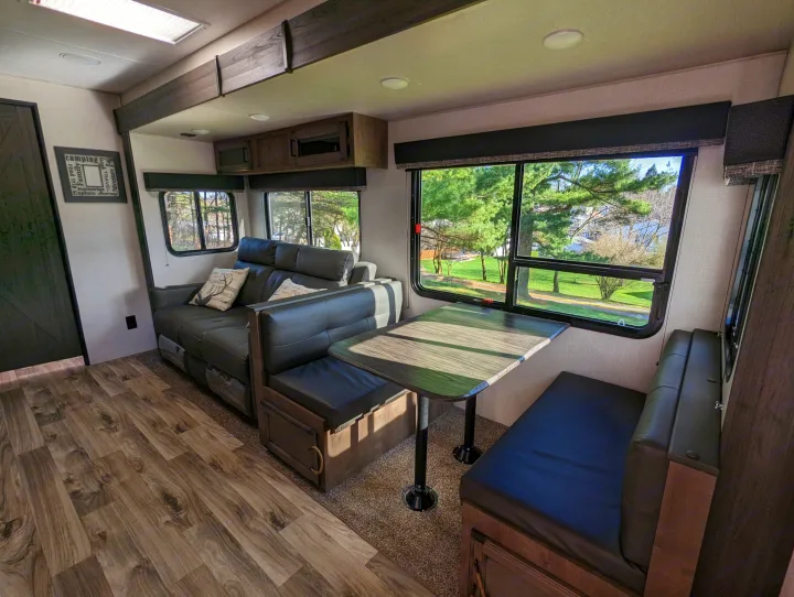 RV rental interior: Spacious living and dining area with a sofa, booth, table, and large windows.. Sport Trek Sport Trek Trailer 2021