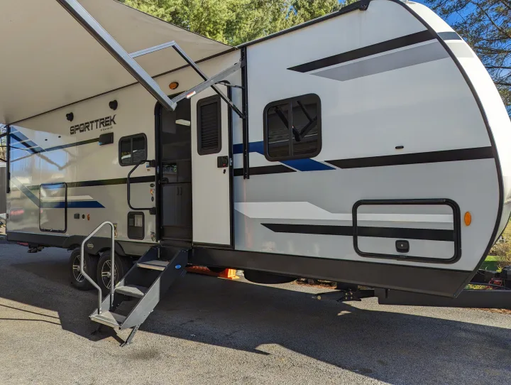 This SportTrek travel trailer, available for rv rental, shows its extended awning and open door, ready for adventure.. Sport Trek Sport Trek Trailer 2021