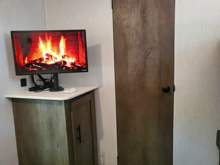RV rental: Warm fireplace display on TV in cozy interior with cabinet and door.. Forest River Wildwood X-Lite 2022