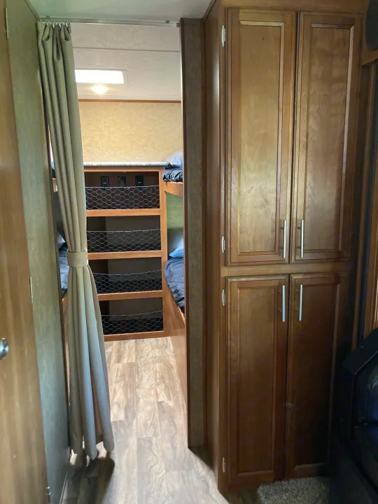 RV rental: View inside, showing bunk beds with storage netting and a tall wood cabinet unit.. Forest River Tracer Air 2016