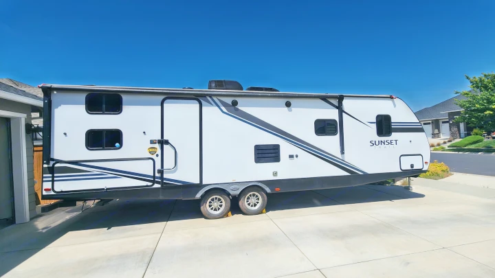 White Sunset Trail travel trailer RV, an ideal rv rental, parked on a sunny concrete driveway.. Crossroads RV Sunset Trail Super Lite 2019