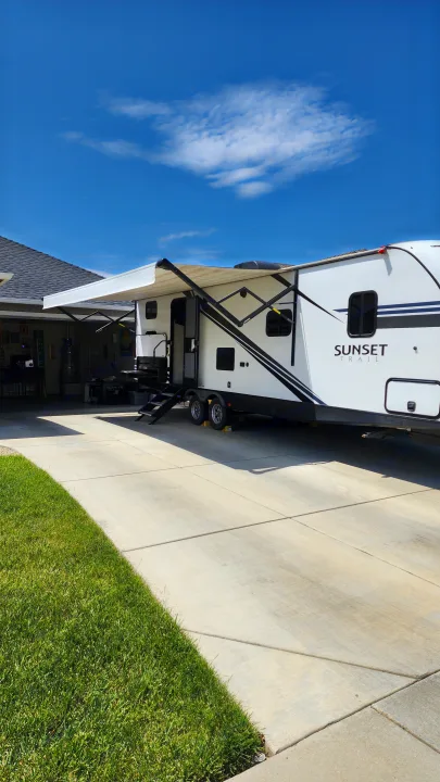 A white Sunset Trail RV rental with an extended awning is parked in a sunny driveway, ready for adventure.. Crossroads RV Sunset Trail Super Lite 2019