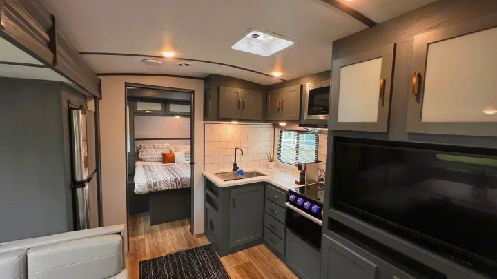 Modern RV rental interior with a compact, stylish kitchen, cozy bedroom, and entertainment area. Ideal for travel.. Keystone RV Bullet Ultra Lite 2022