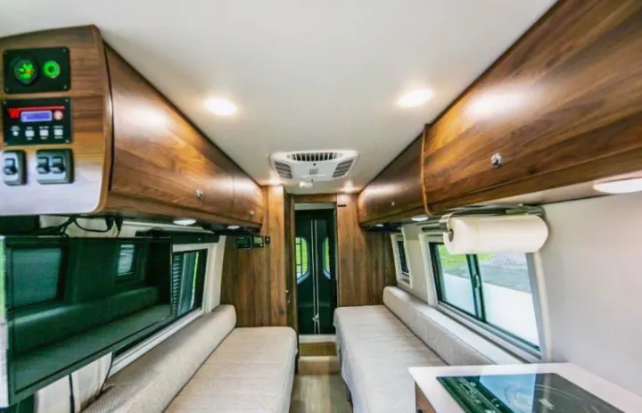 Spacious RV rental interior shows living area with convertible beds, kitchenette, and ample overhead storage cabinets.. Winnebago Boldt 2020