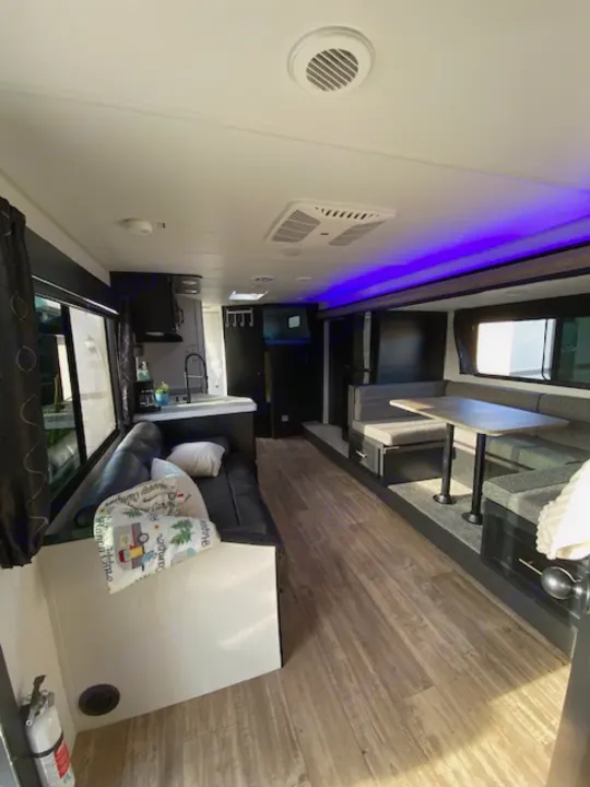 Explore this modern rv rental interior with blue accent lighting, a comfortable sofa, and stylish wood-look floors.. Forest River Cherokee Grey Wolf 2022