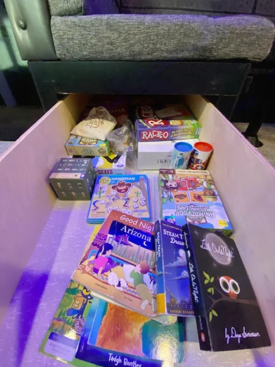 RV rental storage: A drawer under the couch holds games like Racko & kids' books for travel fun.. Forest River Cherokee Grey Wolf 2022