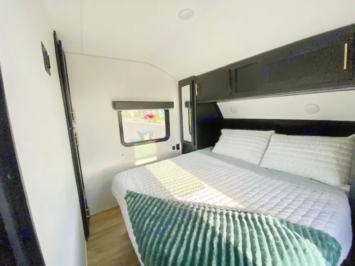 Modern RV rental bedroom with a cozy bed, sleek black cabinets, and a window view, perfect for travel.. Forest River Cherokee Grey Wolf 2022
