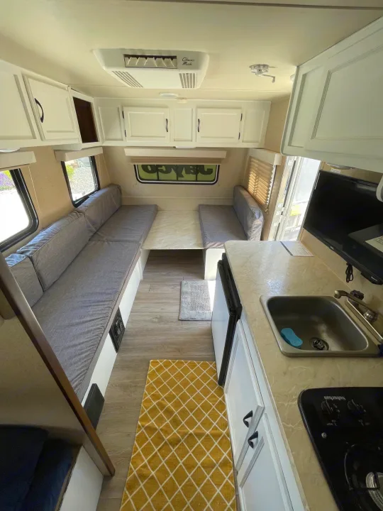 Bright RV rental interior shows kitchen, dinette seating, overhead cabinets, and AC. Ready for comfortable road trips.. Jayco Jay Flight SLX 2015
