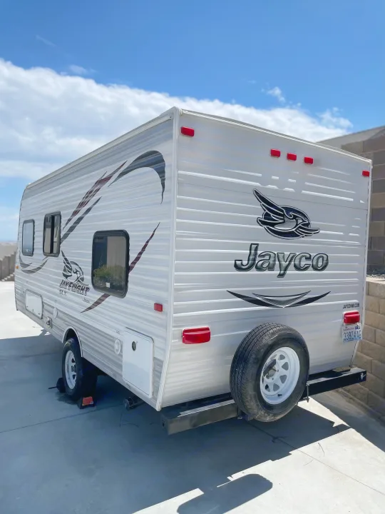 A sleek white Jayco travel trailer, ideal for an RV rental getaway. Parked on concrete under a blue sky.. Jayco Jay Flight SLX 2015
