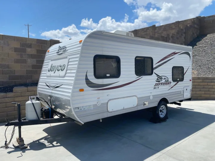 White Jayco Jay Flight SLX travel trailer parked on concrete under blue skies, perfect for your next RV rental or camping trip.. Jayco Jay Flight SLX 2015