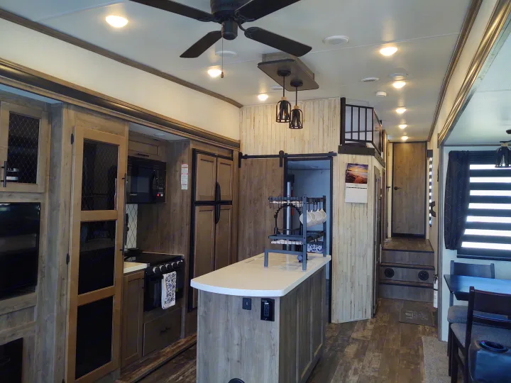 Explore this modern RV rental interior: a full kitchen, dining area, and loft bedroom, ideal for spacious travel.. Forest River Sabre 2021