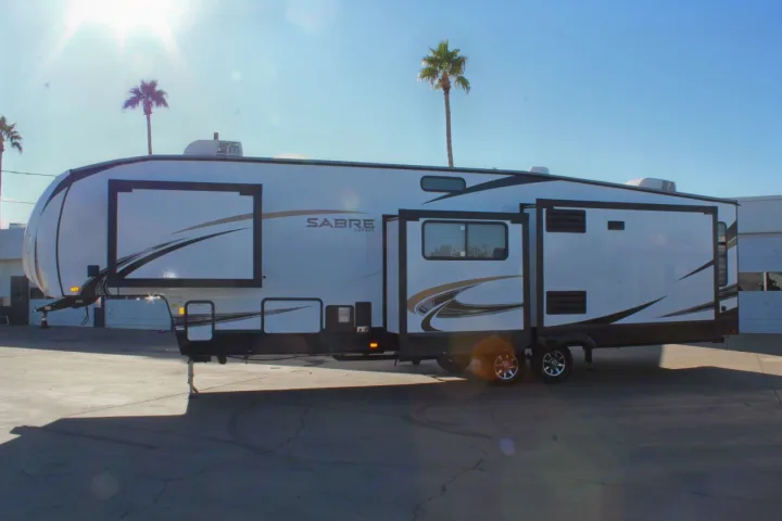 Spacious white Sabre Cobalt fifth-wheel RV rental parked outside on a sunny day with palm trees.. Forest River Sabre 2021