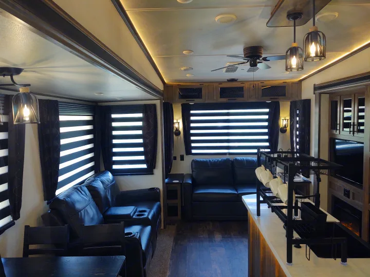 Spacious, modern RV rental interior featuring comfortable recliners, unique zebra blinds, and stylish lighting for luxurious travel.. Forest River Sabre 2021